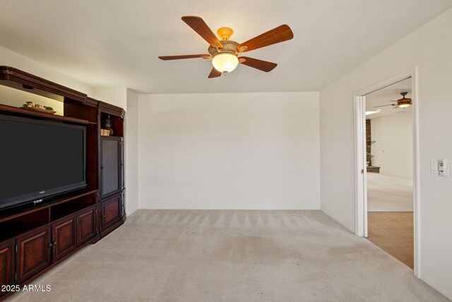 unfurnished living room featuring light carpet and ceiling fan