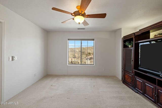 unfurnished living room featuring light carpet, visible vents, a textured ceiling, and a ceiling fan