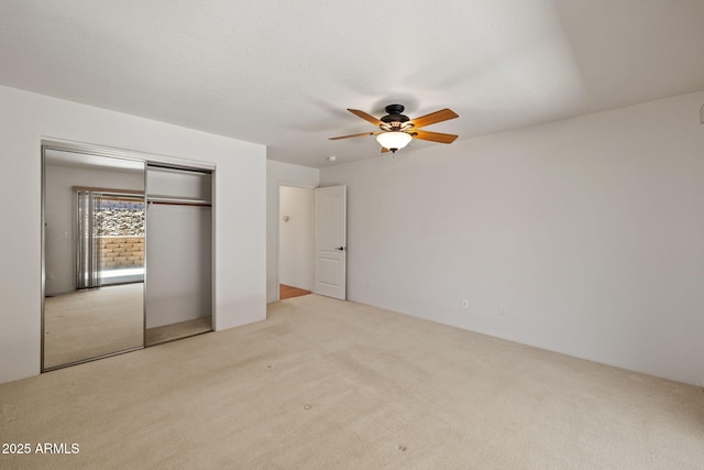 unfurnished bedroom with a closet, light carpet, and a ceiling fan