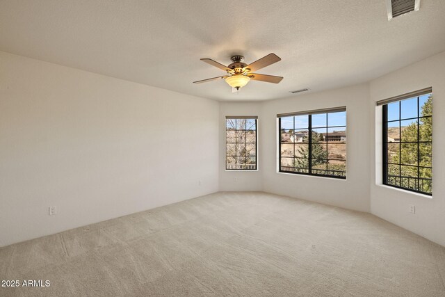 unfurnished room featuring carpet flooring, a ceiling fan, visible vents, and a textured ceiling