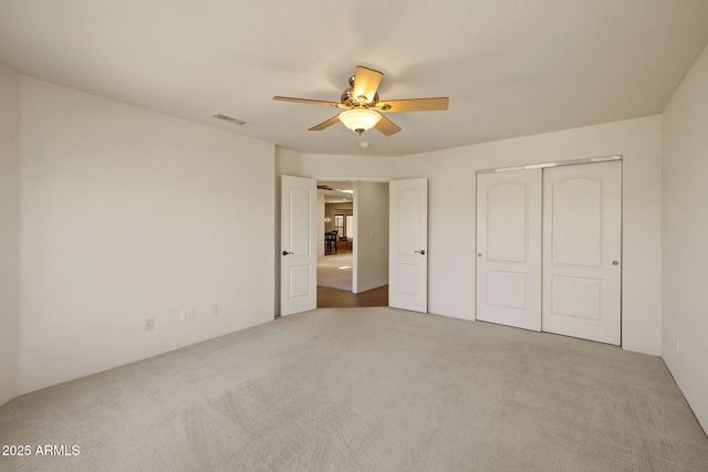 unfurnished bedroom with visible vents, carpet, a closet, and a ceiling fan