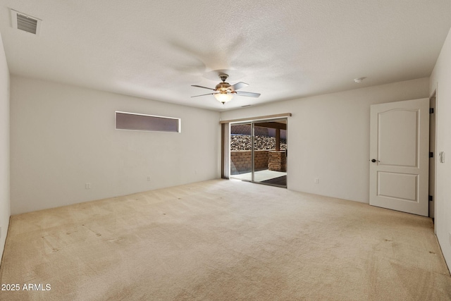 carpeted empty room featuring visible vents, a textured ceiling, and a ceiling fan