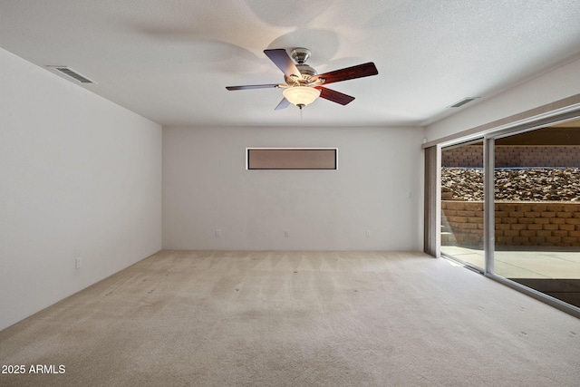 empty room featuring visible vents, a textured ceiling, and carpet flooring