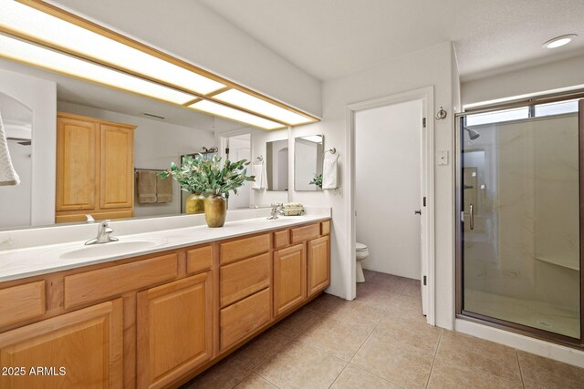 bathroom with tile patterned floors, toilet, a stall shower, a sink, and double vanity