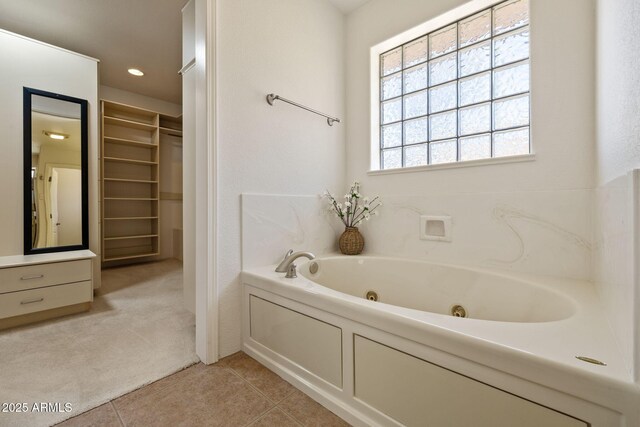 bathroom with tile patterned floors, a jetted tub, a spacious closet, and recessed lighting