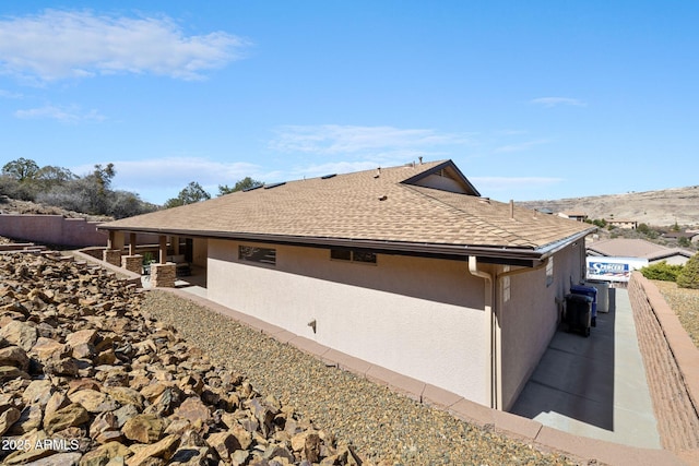 view of side of property featuring a shingled roof and stucco siding