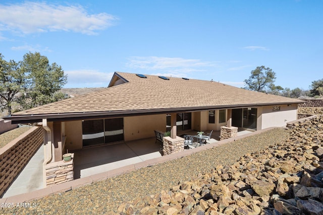 back of house featuring a patio and roof with shingles