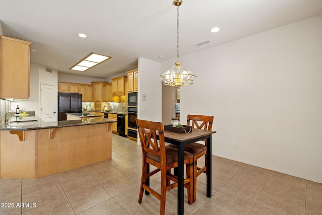 kitchen with light tile patterned floors, visible vents, a peninsula, a sink, and black appliances