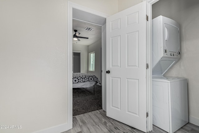 clothes washing area with light hardwood / wood-style flooring, stacked washer and clothes dryer, and ceiling fan