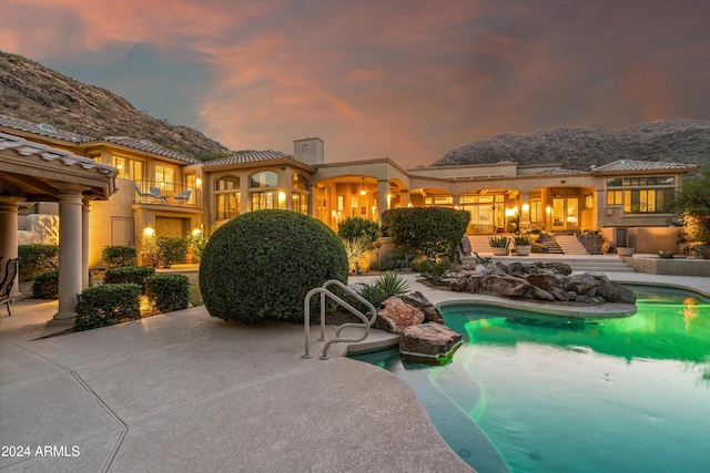 pool at dusk featuring a mountain view and a patio