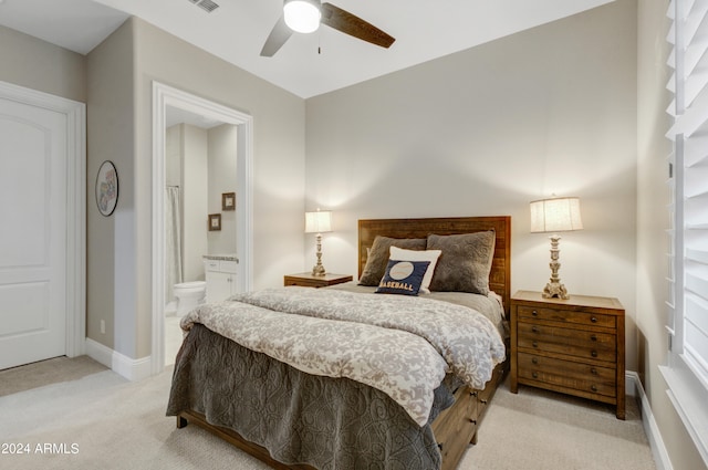 bedroom featuring ceiling fan, light colored carpet, and ensuite bathroom