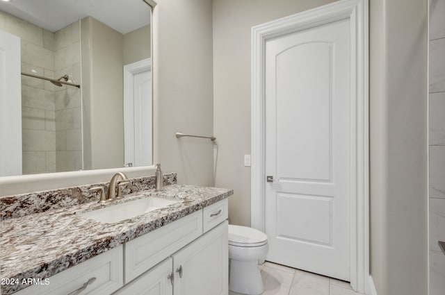 bathroom with a tile shower, vanity, and toilet