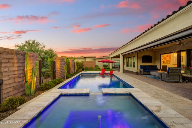 patio terrace at dusk featuring ceiling fan and a swimming pool with hot tub