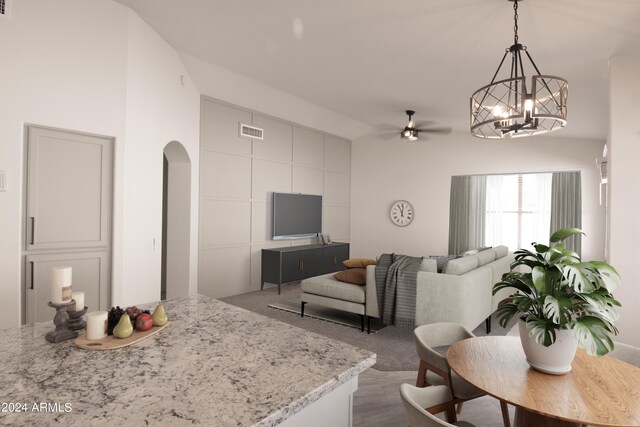 kitchen with ceiling fan, pendant lighting, light colored carpet, and light stone countertops