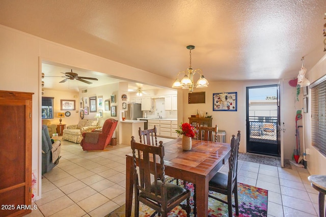 dining space with light tile patterned floors, ceiling fan with notable chandelier, sink, and a textured ceiling