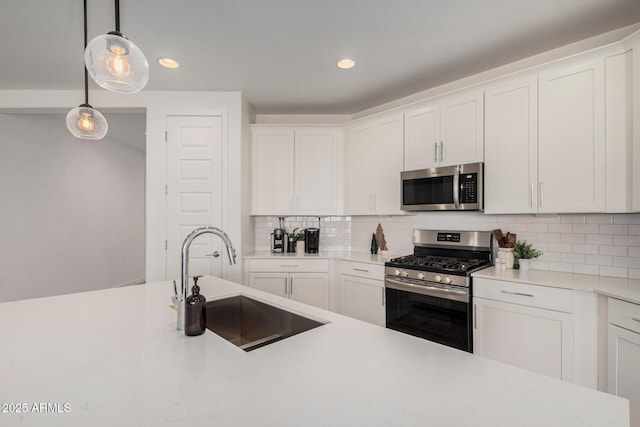 kitchen featuring white cabinets, sink, tasteful backsplash, decorative light fixtures, and stainless steel appliances