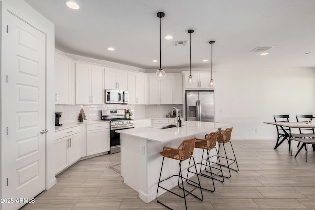 kitchen featuring appliances with stainless steel finishes, white cabinetry, a kitchen island with sink, and sink