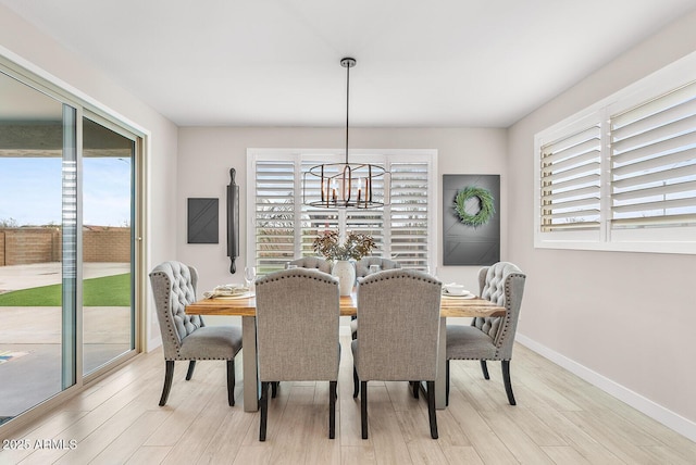 dining space featuring light wood-type flooring, baseboards, and a notable chandelier