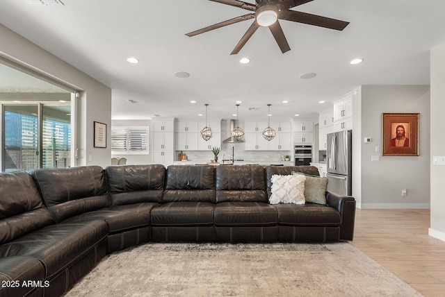 living area featuring recessed lighting, baseboards, light wood-style flooring, and ceiling fan