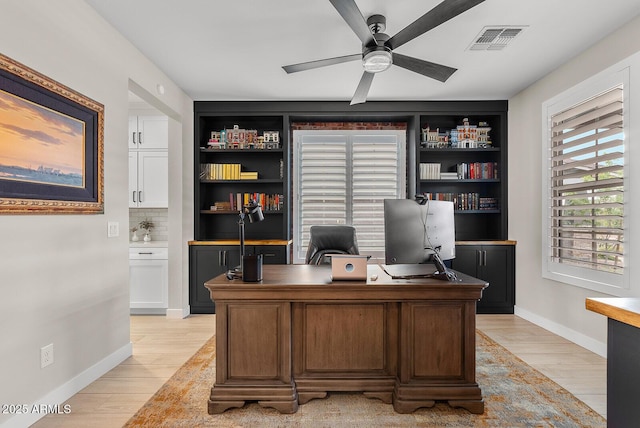 office area with visible vents, baseboards, light wood-style floors, and ceiling fan