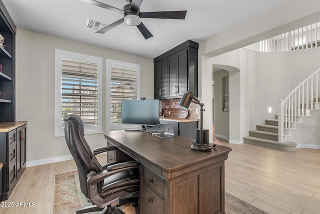 office area with a ceiling fan, baseboards, visible vents, arched walkways, and light wood-type flooring