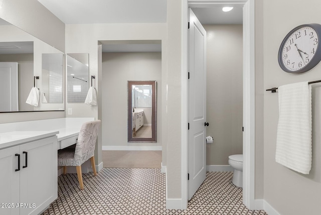 bathroom with toilet, vanity, and baseboards