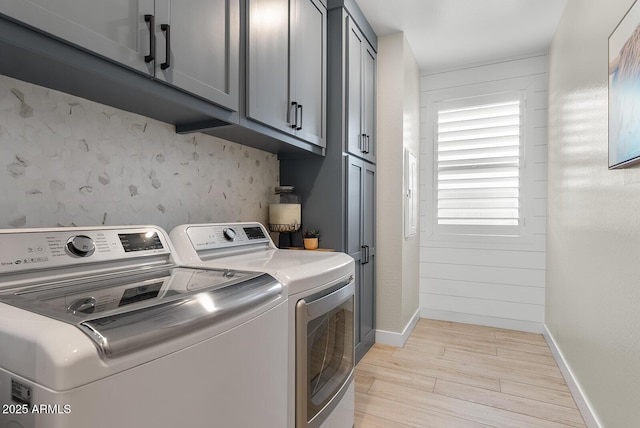 laundry room featuring washer and clothes dryer, cabinet space, baseboards, and light wood-style floors