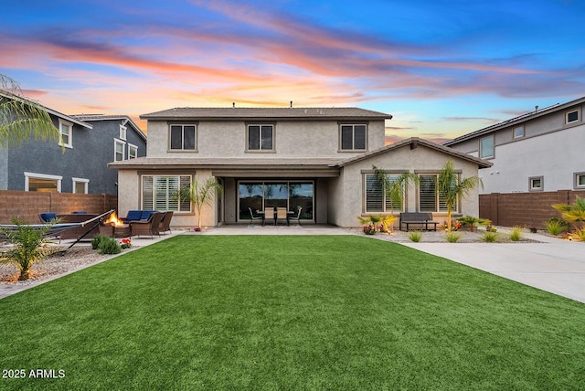 back of property at dusk with a patio area, stucco siding, a lawn, and fence