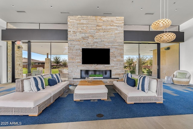 living room with wood finished floors, visible vents, a wealth of natural light, and an outdoor stone fireplace