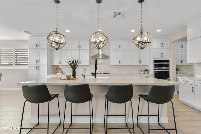 kitchen with stainless steel double oven, white cabinetry, light countertops, and visible vents