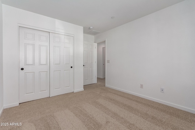 unfurnished bedroom with light carpet and a closet