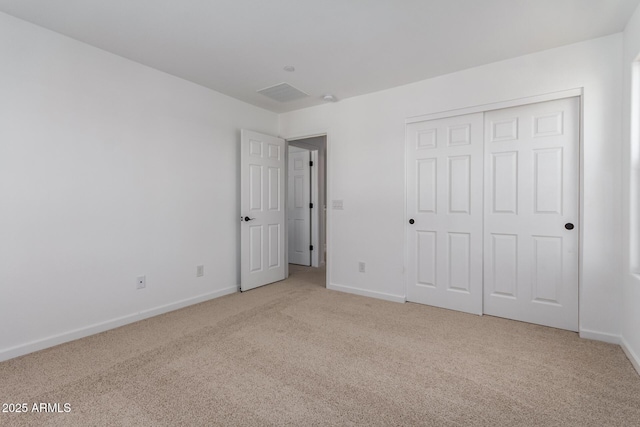 unfurnished bedroom featuring light colored carpet and a closet