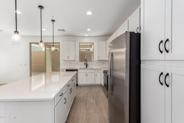 kitchen featuring sink, white cabinets, hanging light fixtures, a center island, and stainless steel appliances