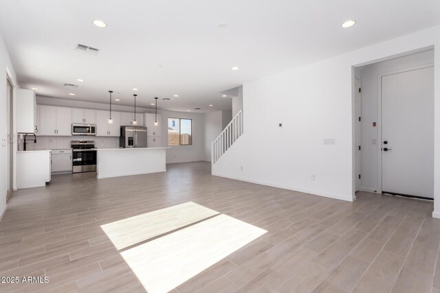 unfurnished living room featuring sink and light hardwood / wood-style floors