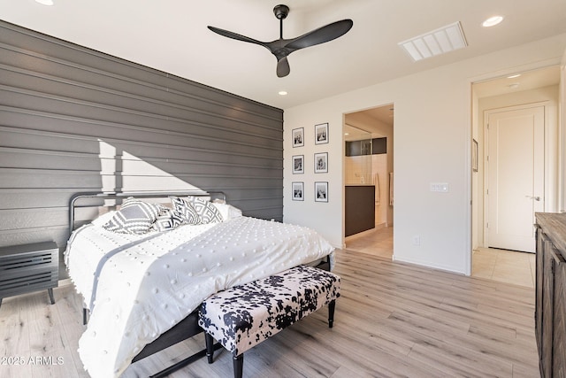 bedroom with ceiling fan, connected bathroom, and light hardwood / wood-style flooring