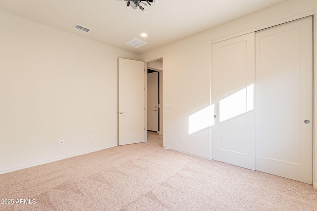 unfurnished bedroom with a closet and light colored carpet