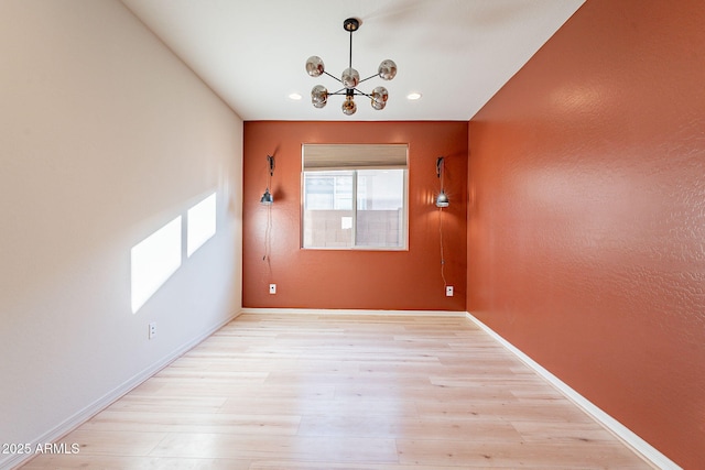 unfurnished room featuring a chandelier and light hardwood / wood-style flooring