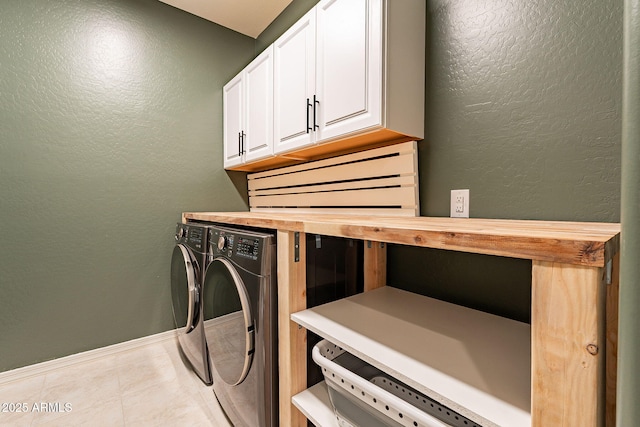 laundry area with washing machine and dryer, light tile patterned floors, and cabinets