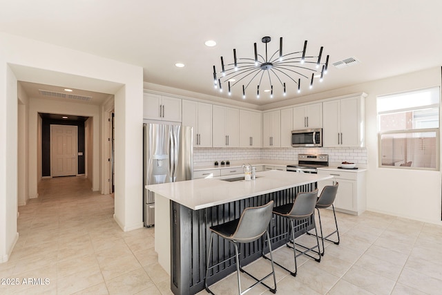 kitchen featuring sink, white cabinetry, an island with sink, and appliances with stainless steel finishes