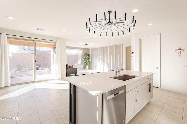 kitchen featuring stainless steel dishwasher, white cabinetry, sink, and a kitchen island with sink