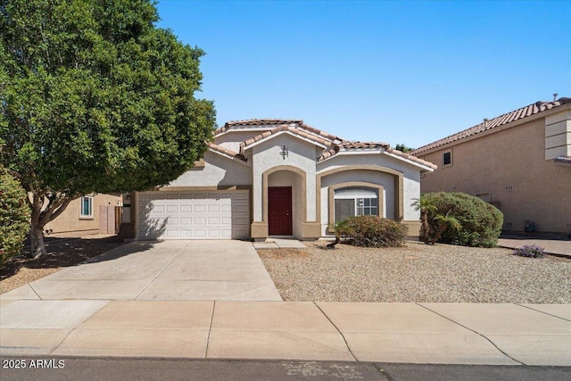 mediterranean / spanish house featuring driveway, stucco siding, an attached garage, and a tiled roof