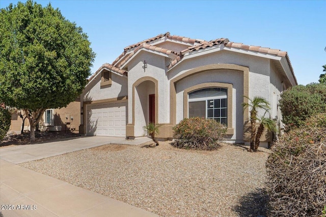 view of front of property with driveway, a tiled roof, a garage, and stucco siding