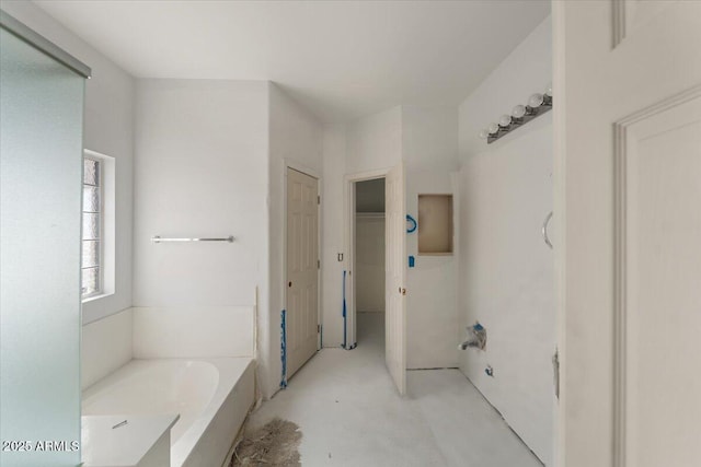 full bathroom with a closet, concrete floors, and a bath