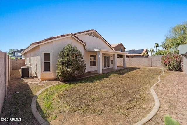 rear view of property with stucco siding, a fenced backyard, a lawn, and central air condition unit