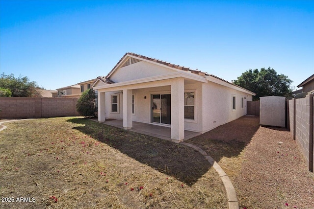 rear view of property with a yard, a fenced backyard, a patio, and stucco siding