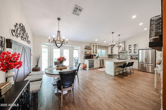 9085 E Windrose Dr, Scottsdale, AZ 85260 - dining area with a chandelier, vaulted ceiling, beverage cooler, plenty of natural light, and recessed lighting