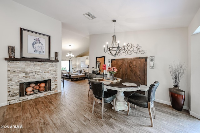 9085 E Windrose Dr, Scottsdale, AZ 85260 - dining area with a chandelier, wood finished floors, a stone fireplace, and high vaulted ceiling