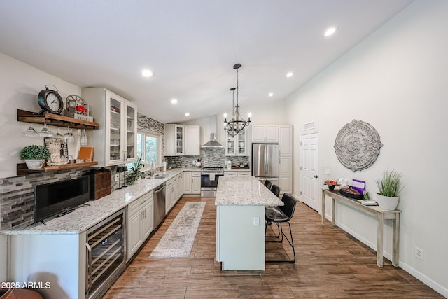9085 E Windrose Dr, Scottsdale, AZ 85260 - kitchen with stainless steel appliances, wall chimney exhaust hood, a breakfast bar area, lofted ceiling, and wine cooler