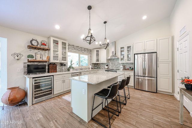 9085 E Windrose Dr, Scottsdale, AZ 85260 - kitchen featuring appliances with stainless steel finishes, beverage cooler, wall chimney range hood, lofted ceiling, and a chandelier