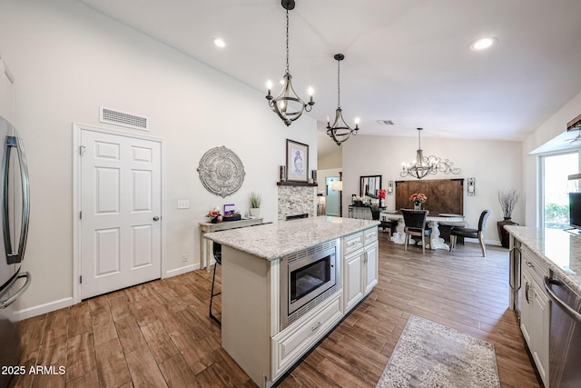 9085 E Windrose Dr, Scottsdale, AZ 85260 - kitchen with stainless steel appliances, a chandelier, wood finished floors, light stone countertops, and recessed lighting